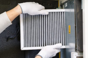 A person replacing a dirty furnace air filter.